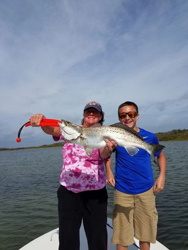 Clients holding a giant seatrout while on an inshore fishing charter